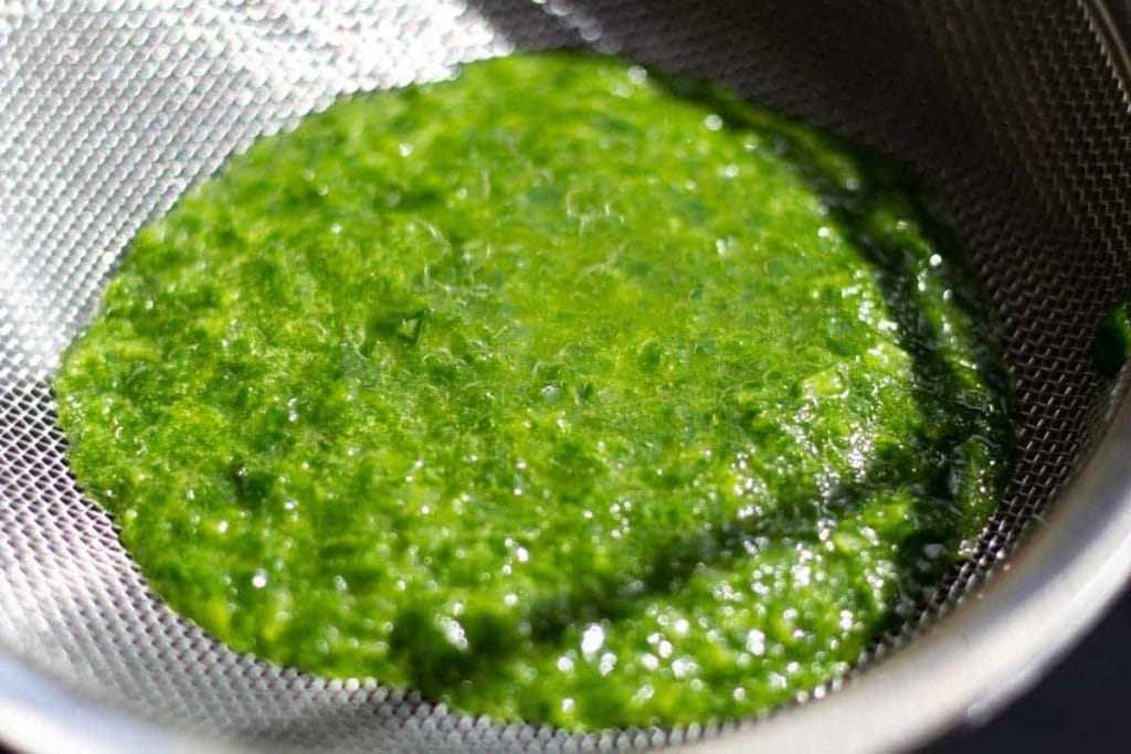 straining the wild garlic pulp from the il using a fine sieve