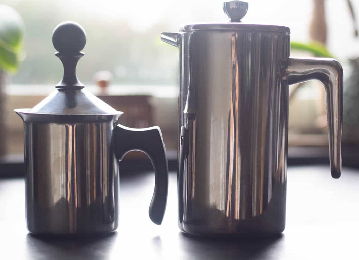 a milk frother beside a french press
