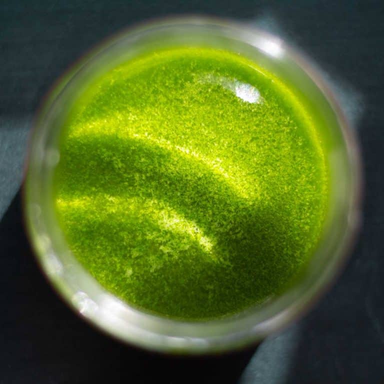 birdseye view of vibrant green wild garlic oil in a jar