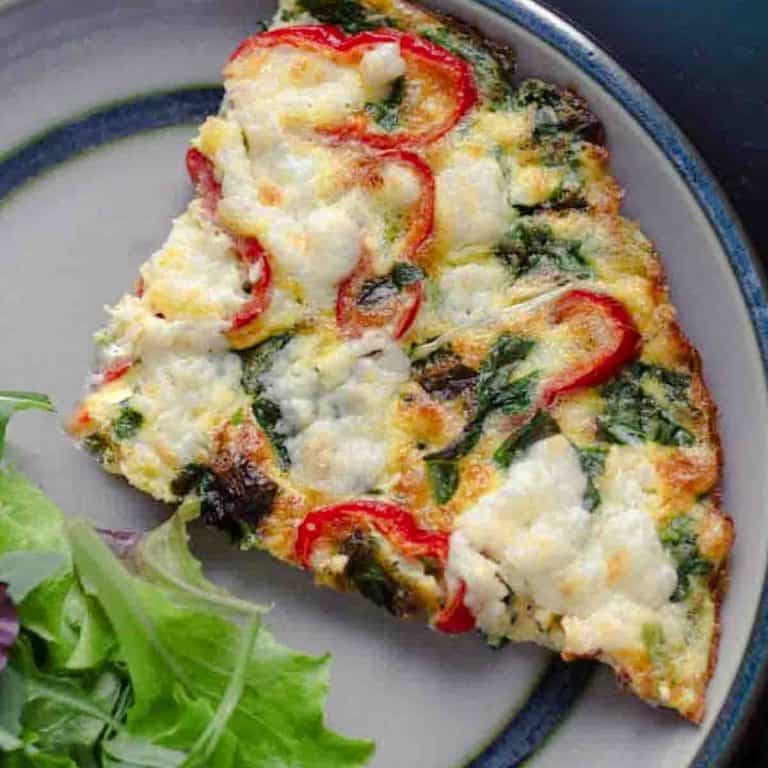 a slice of wild garlic frittataon a ceramic plate iwht a mixed salad
