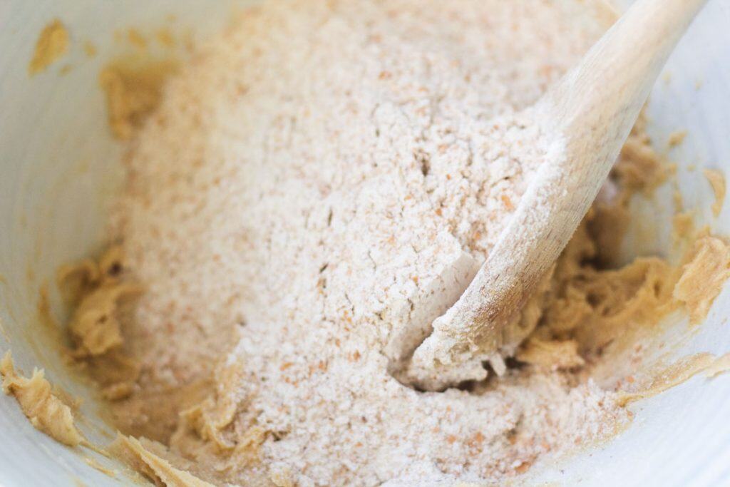 Whole wheat flour was added to creamed butter and brown sugar. Ther is a wooden spoon in the bowl