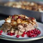Caramelized Cabbage Meatloaf - Swedish Kålpudding served on a cermaic plate with lingonberry sauce. There is a dish of kålpudding in the background