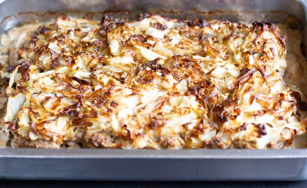 An dish of finished Caramelized cabbage meatloaf - kålpudding that is rich golden brown on top