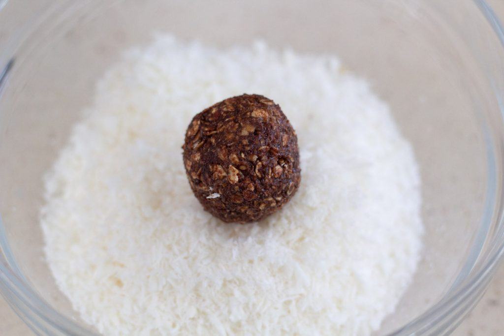 A chocolate ball in a bowl of shredded coconut