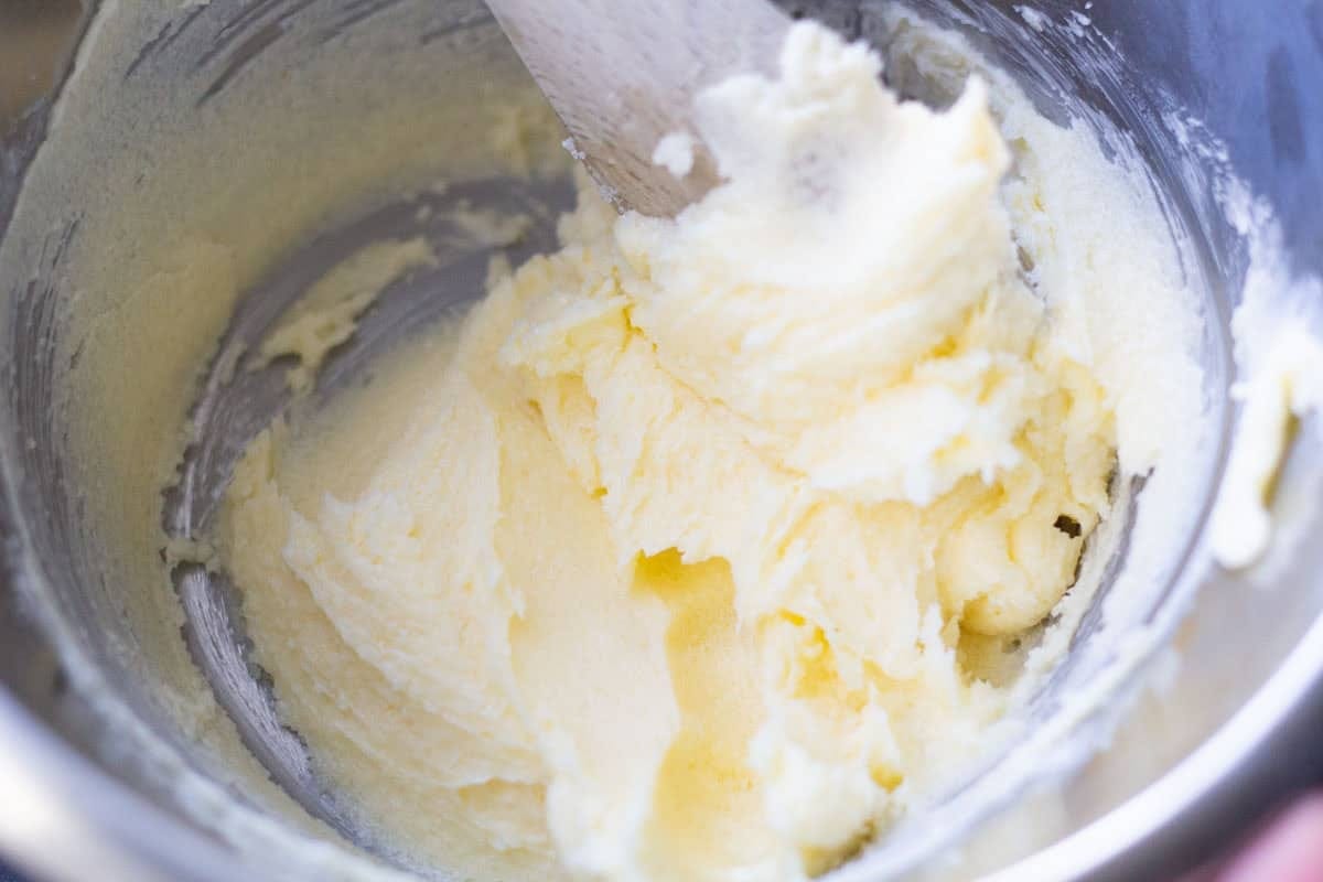 a wooden spoon mixing butter adn sugar together in a medium bowl