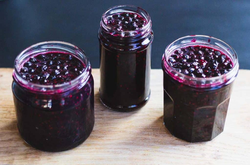 three jars without lids filled with Queen's Jam on a wooden table