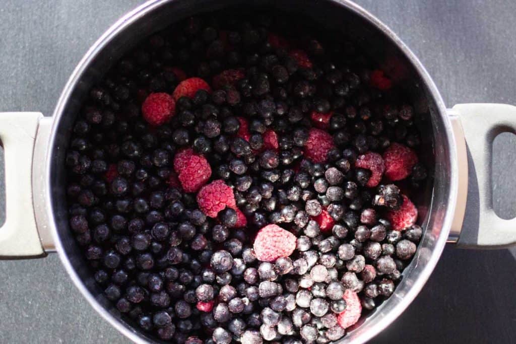 frozen blueberries and raspberries in a large stainless steel pot