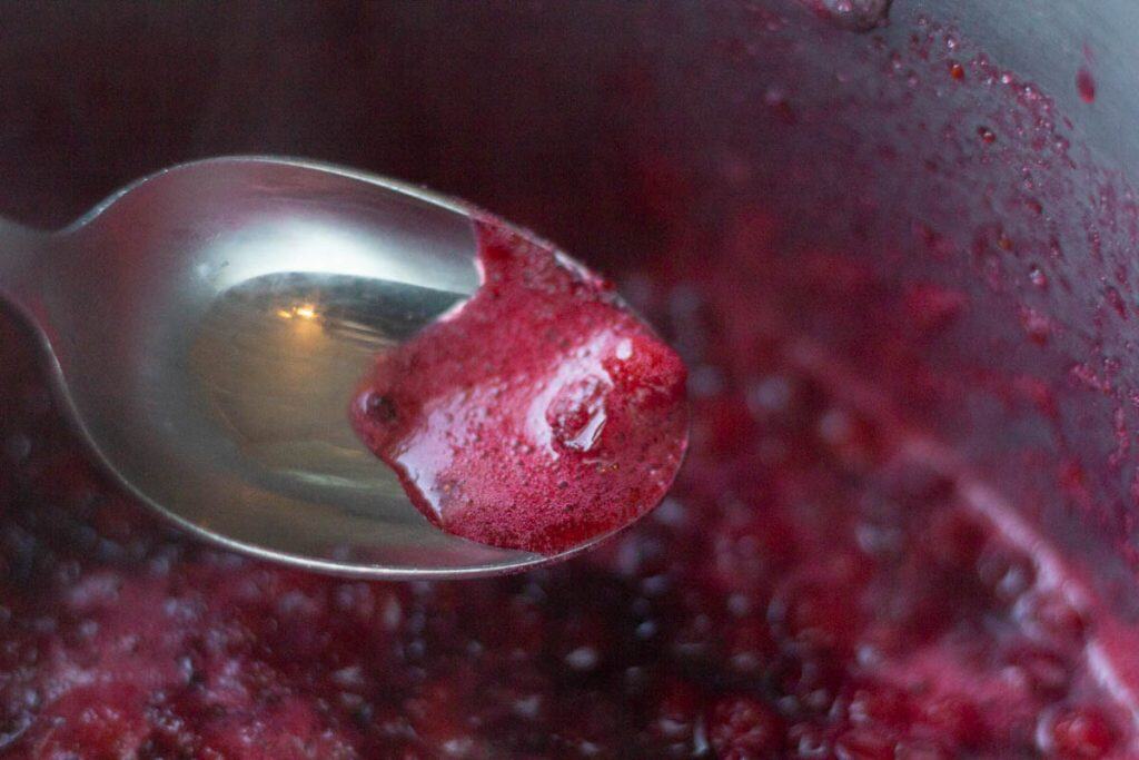 a spoon scooping foam from the jam in a pot