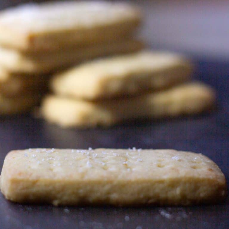 a close up of a salted lemon shortbread cookie with more cookies in the background