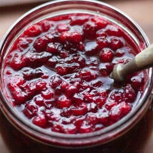 A spoon in Swedish Lingonberry Jam in a glass jar