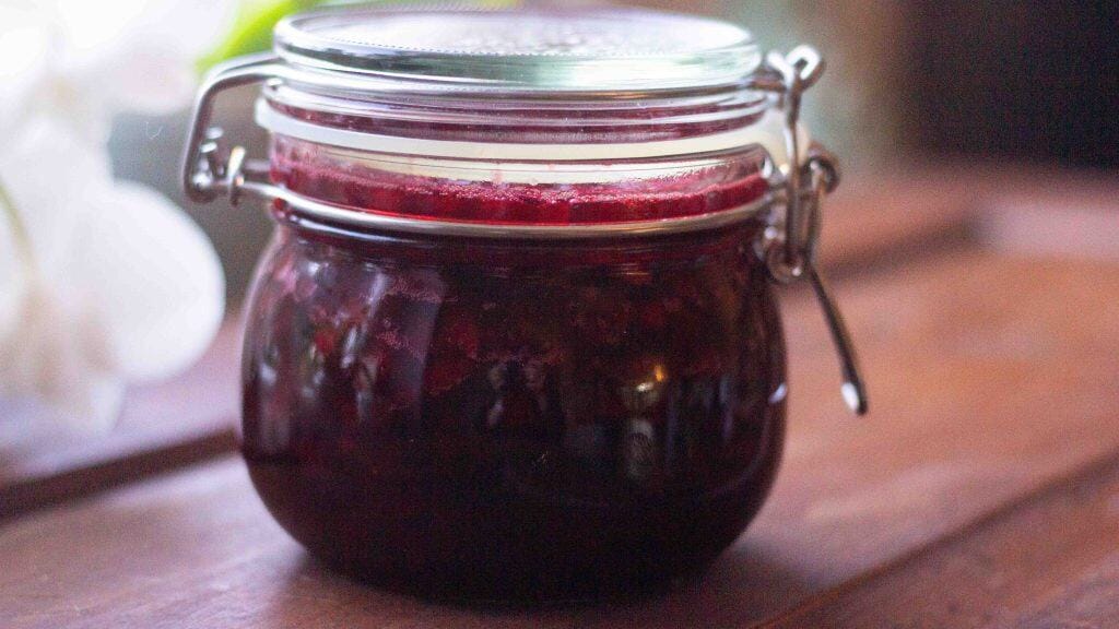 A glass jar of swedish Lingonberry Jam on a wooden table