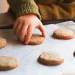 A child's hand picking up a whole wheat shortbread cookie