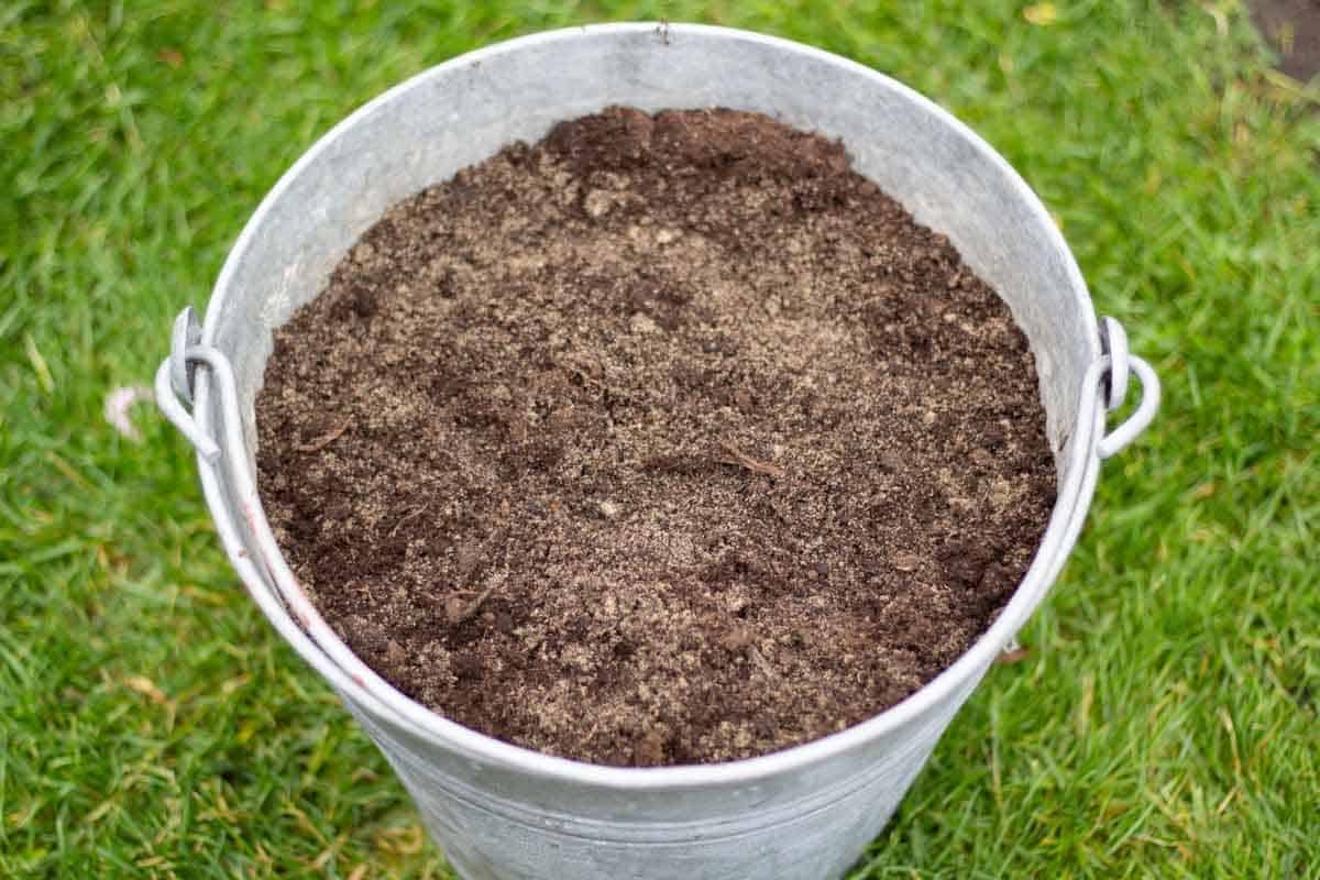 a metal bucket filled with a mixture of soil and sand