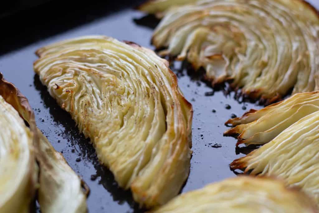 close up of roasted cabbage wedges in a baking tray