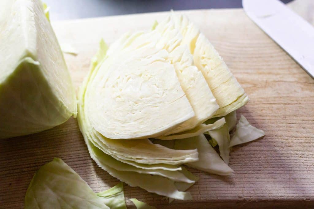 cabbage wedges on a chopping board with a sharp knife