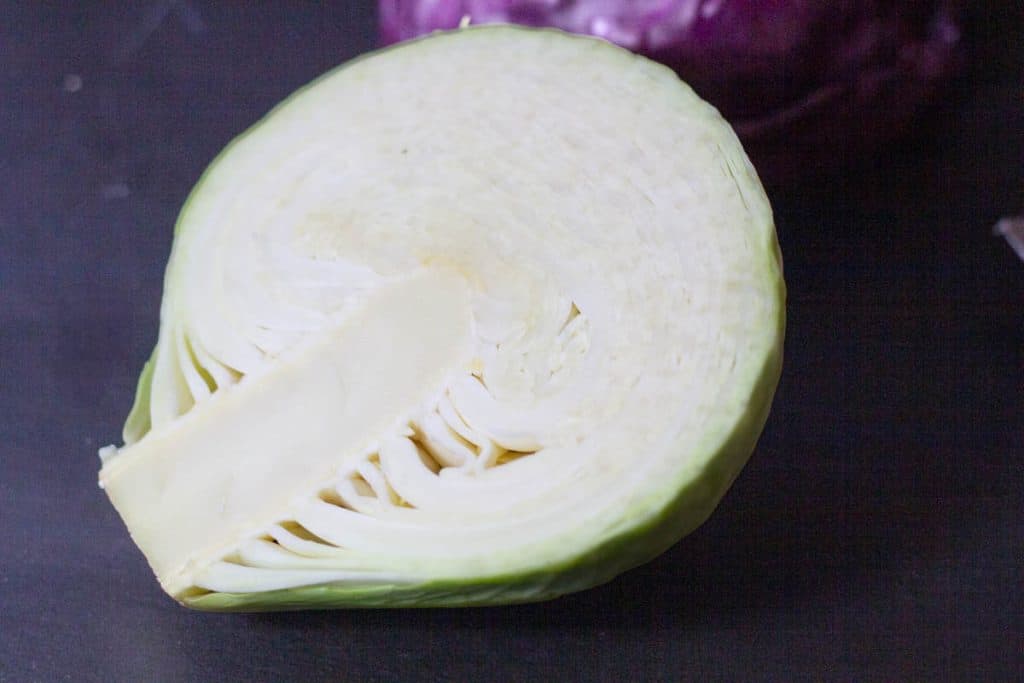 half a head of cababge on a dark table