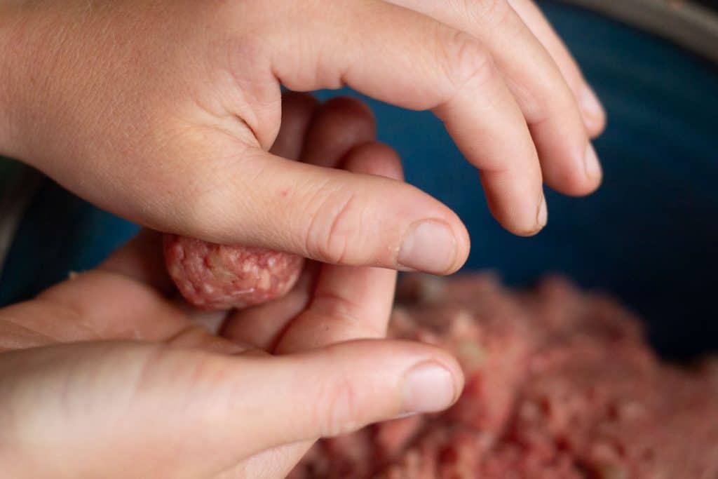 Two hands rolling meatball mixture