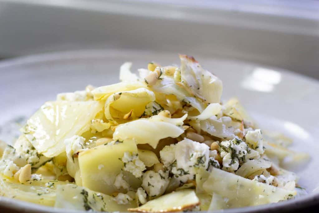 Side view of warm roasted cabbage salad heaped ona white ceramic plate