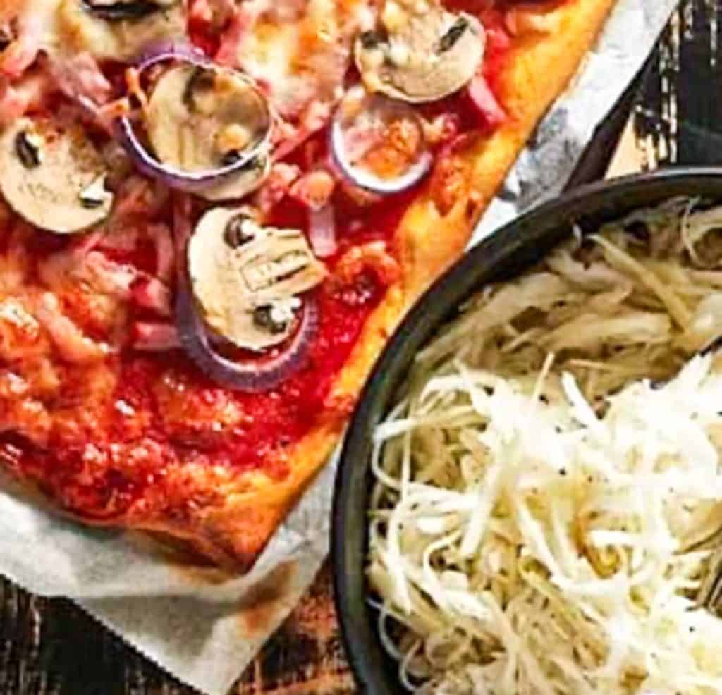 Swedish Pizza salald served in a dark ceramic bowl beside homemade pizza
