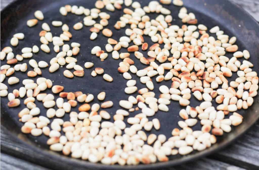 toasted pine nuts in a cast iron skillet