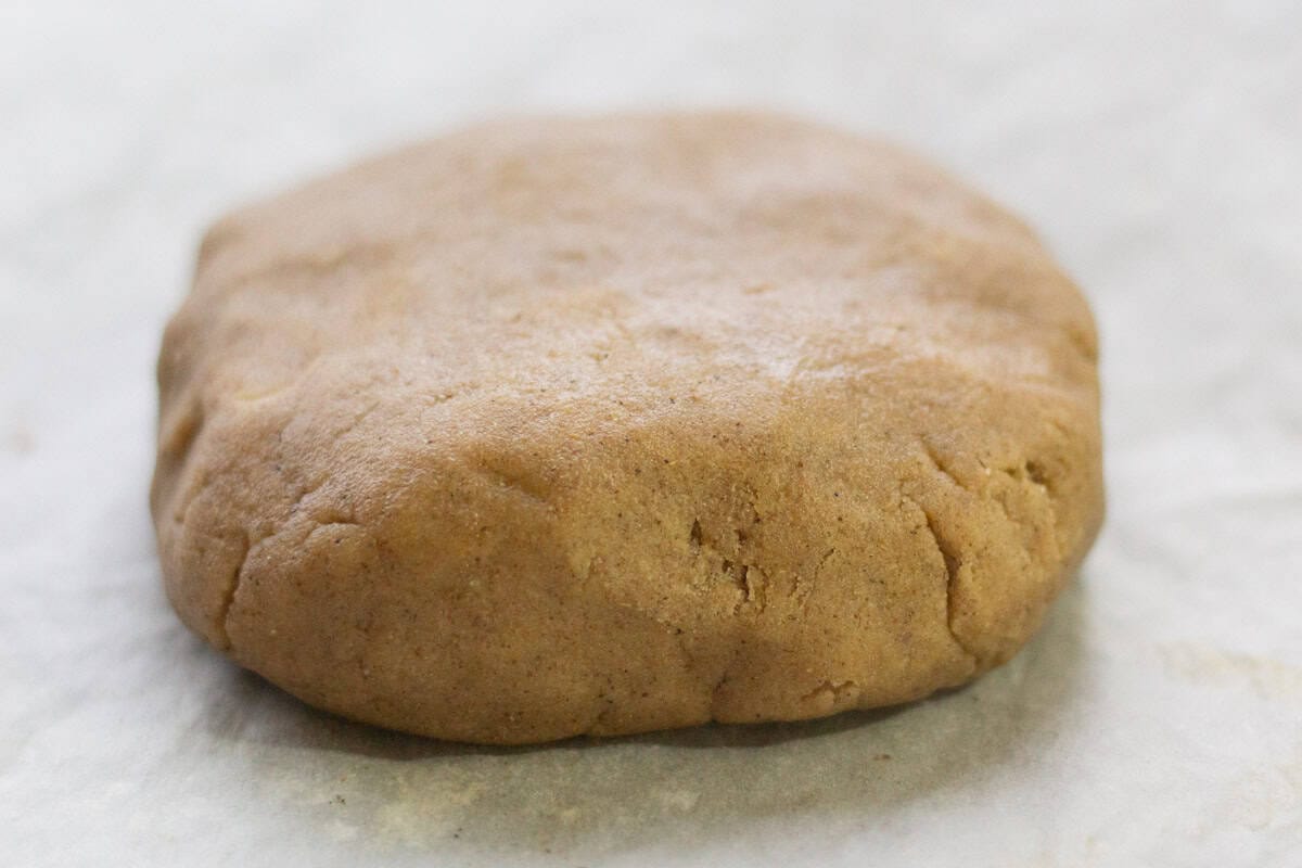 a disc of gingerbread shortbread dough on parchment paper
