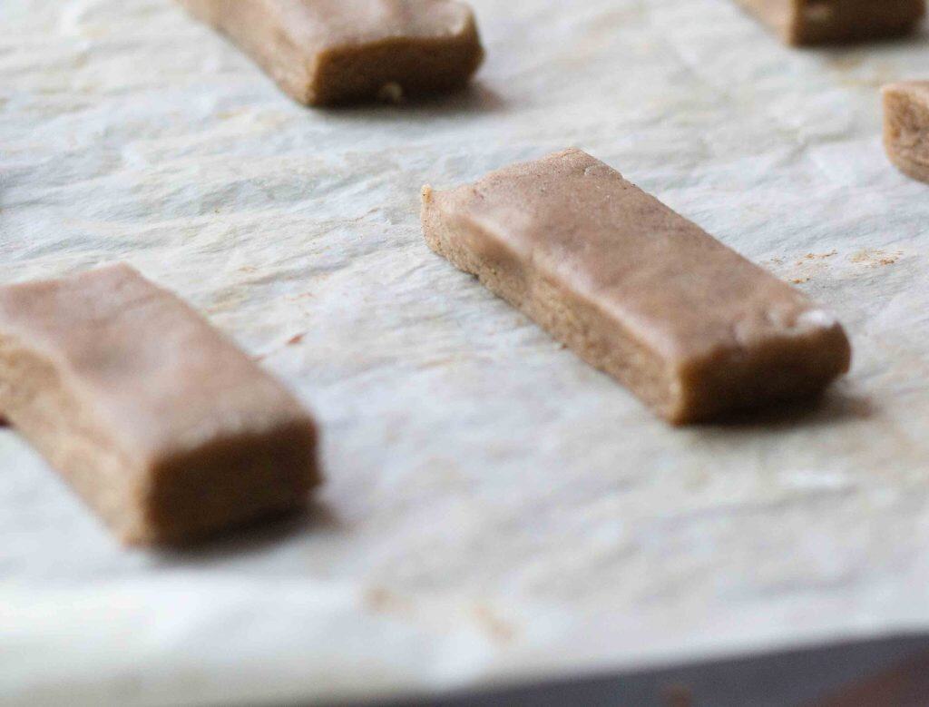 shortbread dough cut into finger shaped and placed on a baking sheet lined with parchment paper