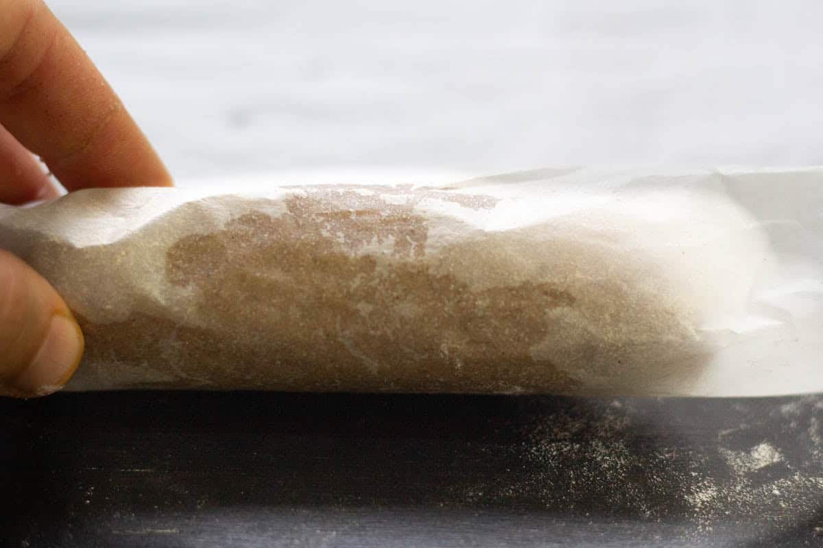 gingerbread shortbread dough rolled to a sausage shape in parchment paper