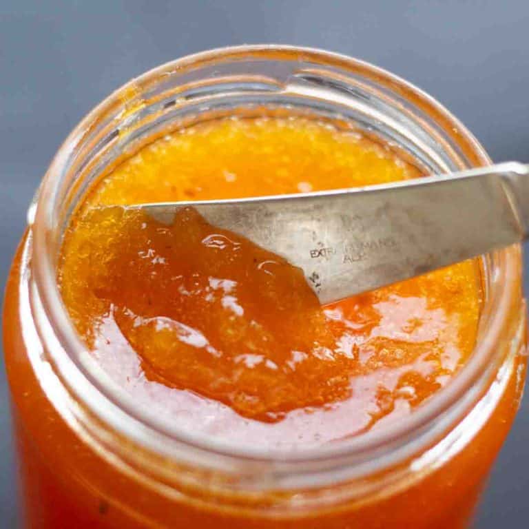 Homemade cloudberry jam in a jar with a silver knife