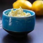 Whipped lemon butter in a blue ceramic ramekin beside fresh lemons