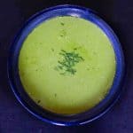 Fresh pea shoot soup in a dark blue ceramic bowl and garnished with chopped chives
