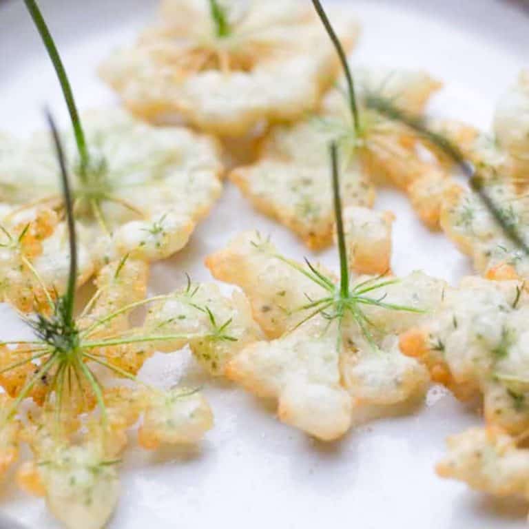golden brown Queen Annes Lace Fritters in a white ceramic plate