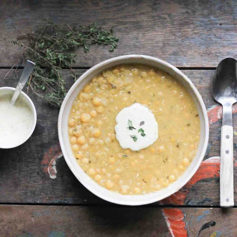 close up of ärtsoppa swedish pea soup served in a rustic white ceramic bowl together with a creamy wholegrain mustard sauce and fresh thyme