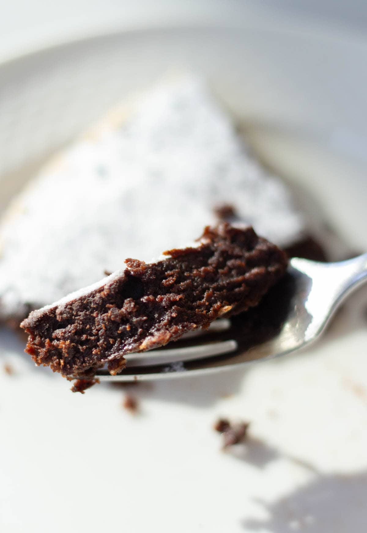 a cose up image of a pice of sticky chocoalte cake on a fork