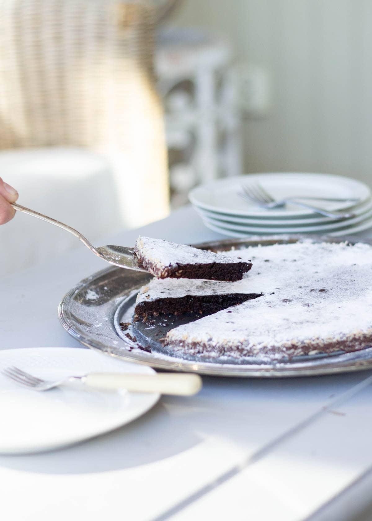 A silver cake slicer serving a lice of swedish kladdkaka
