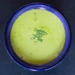 creamy pea shoot soup served in a blue ceramic bowl and garnished with chopped chive
