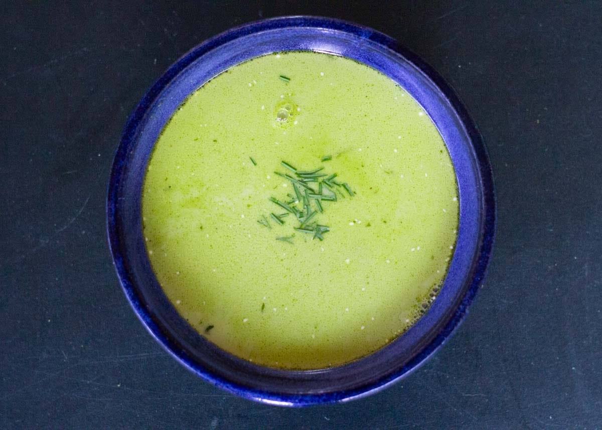 Fresh Nordic green soup in a blue bowl with herbs garnish. ceramic bowl and garnished with chopped chives